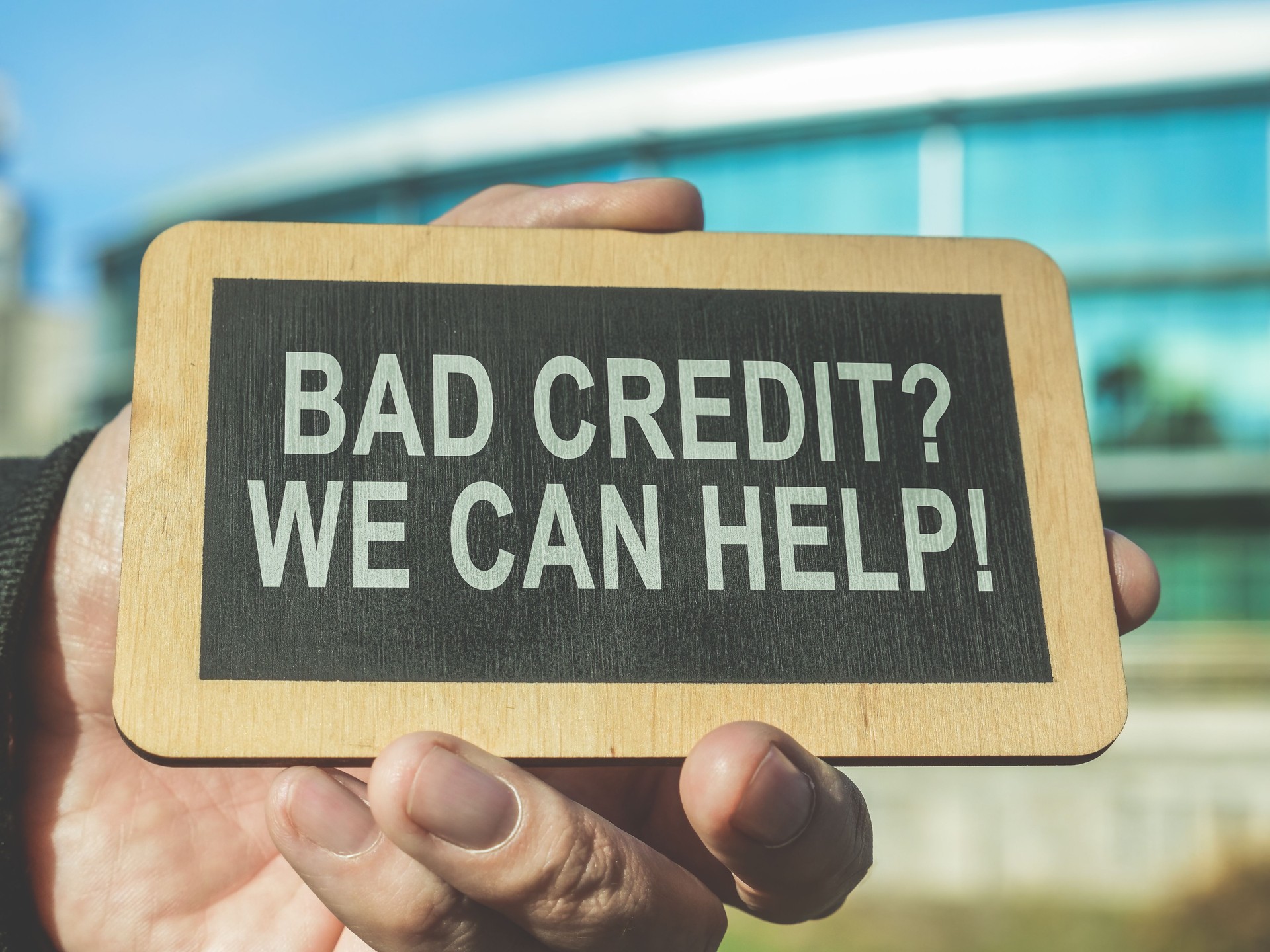 A hand holds a sign Bad credit, we can help.